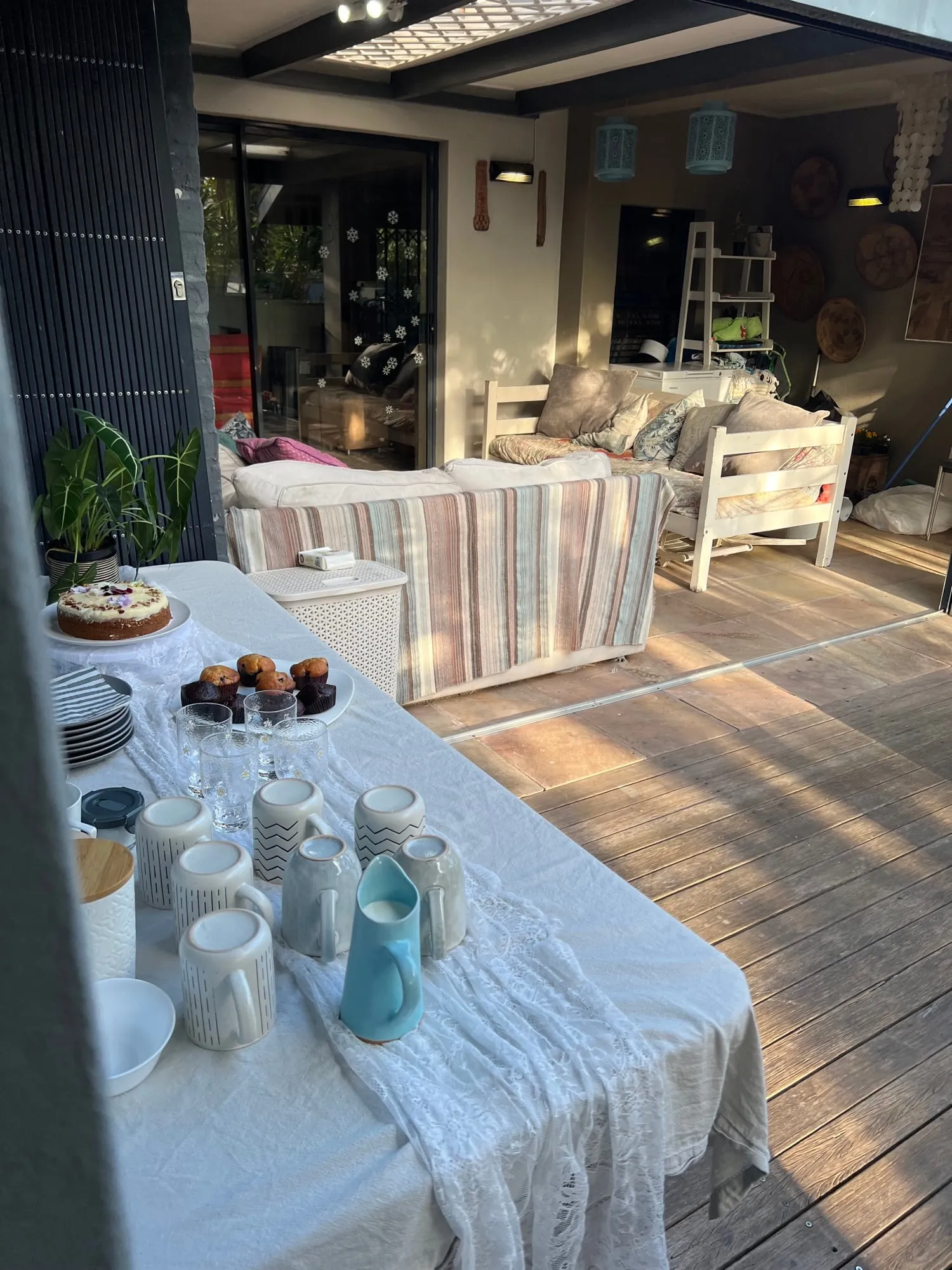 The tea-and-treats table set with cake, muffins and mugs beside the garden studio seating